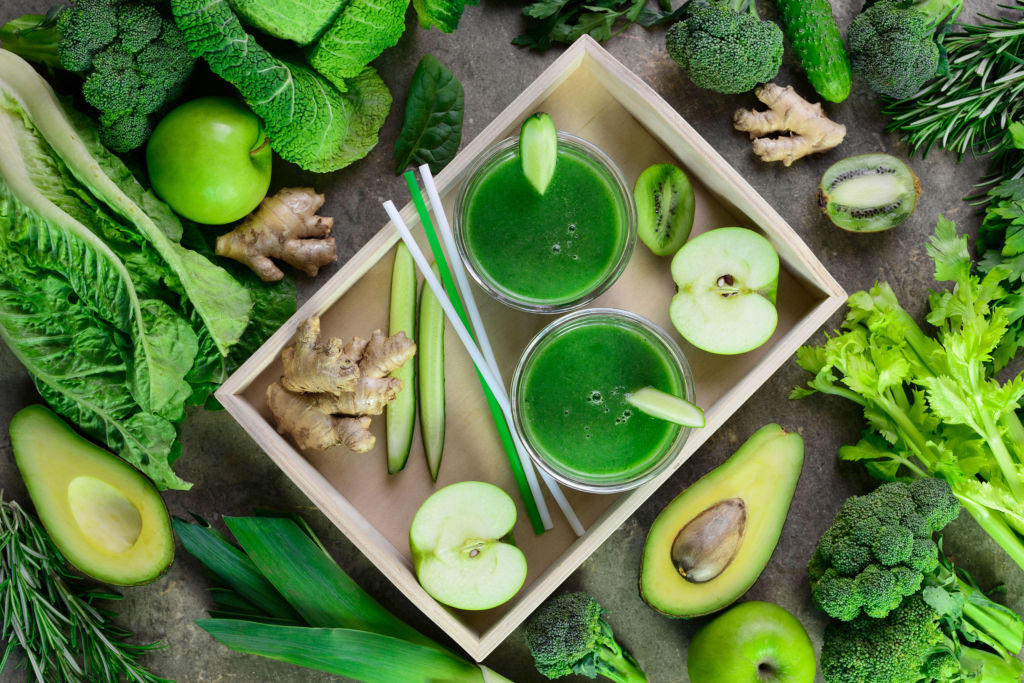 Detox green smoothies concept, two glasses of green diet detox drink  and various fresh green vegetables around them, view from above composition